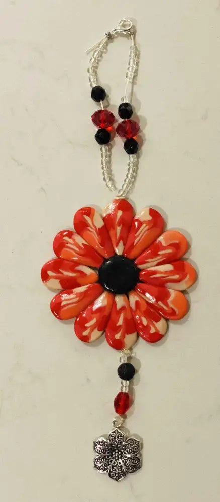 Sofia Daisy polymer clay charm with red petals, black lava bead, and glass beads on an elastic cord.
