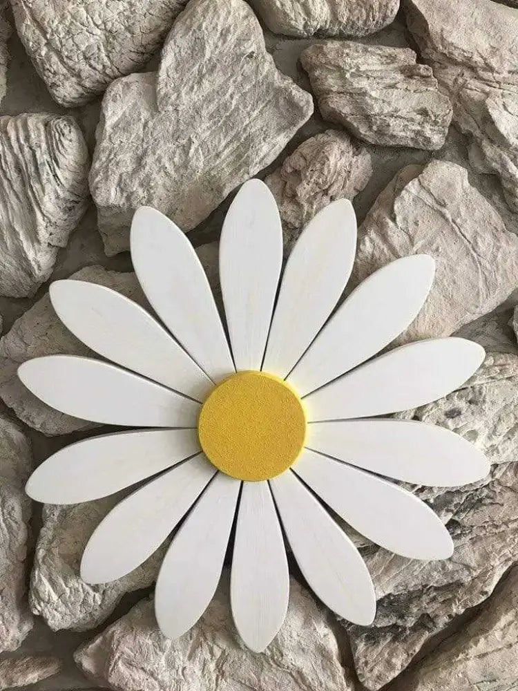 Hand-painted wooden art daisy on a stone background, symbolizing new beginnings and motherhood.