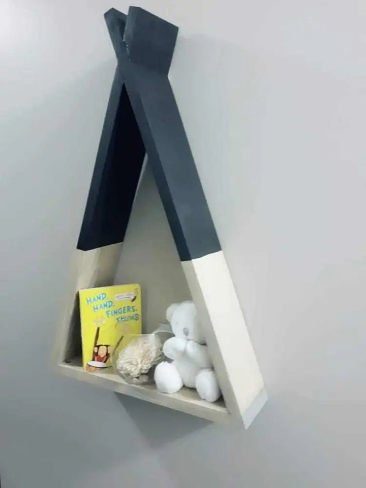 Handcrafted wooden teepee shelf with books and a teddy bear.