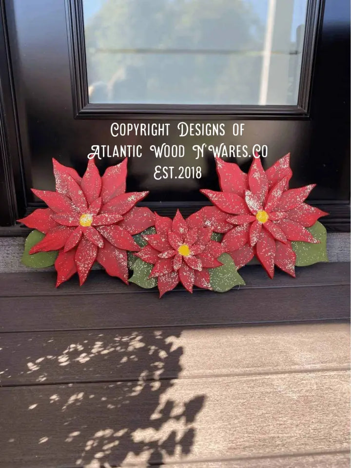 Wooden Poinsettia flowers on display, symbolizing Christmas celebration with vibrant red petals and green leaves.