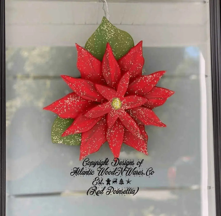 Wooden poinsettia decoration with vibrant red leaves and green foliage, hanging on a door.