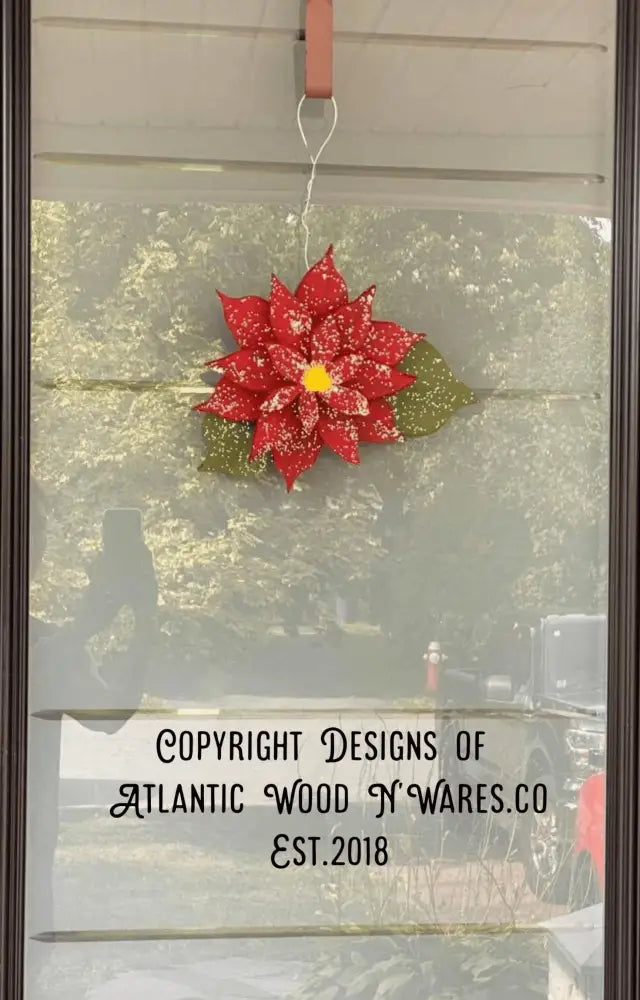 Wooden poinsettia decoration hanging on a glass door.