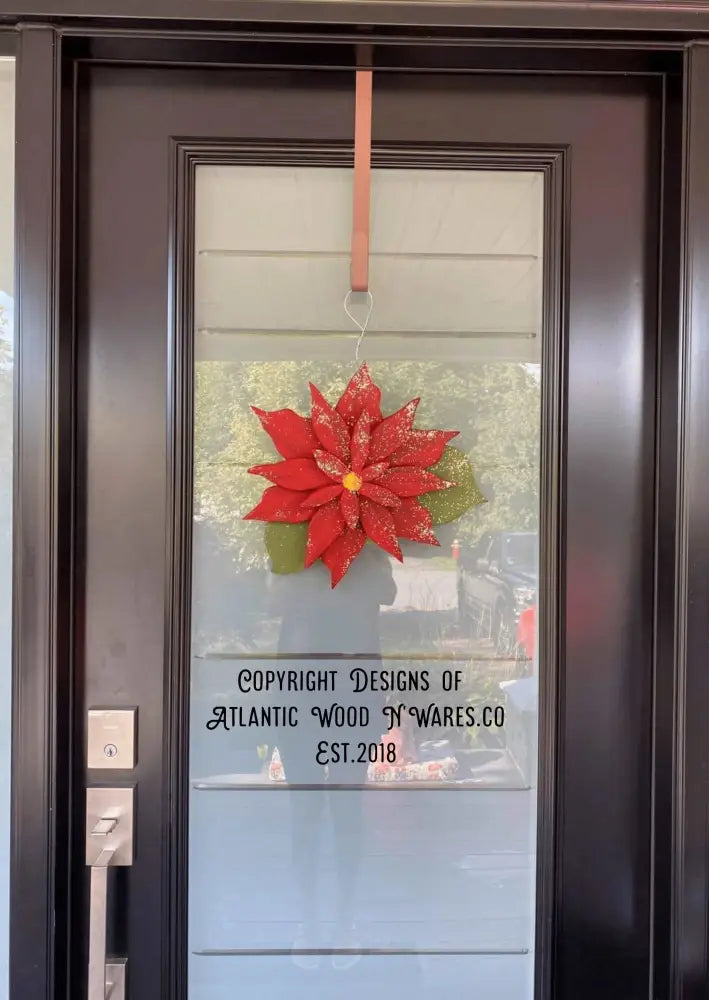Wooden poinsettia decoration hanging on a door, symbolizing Christmas and holiday celebration.