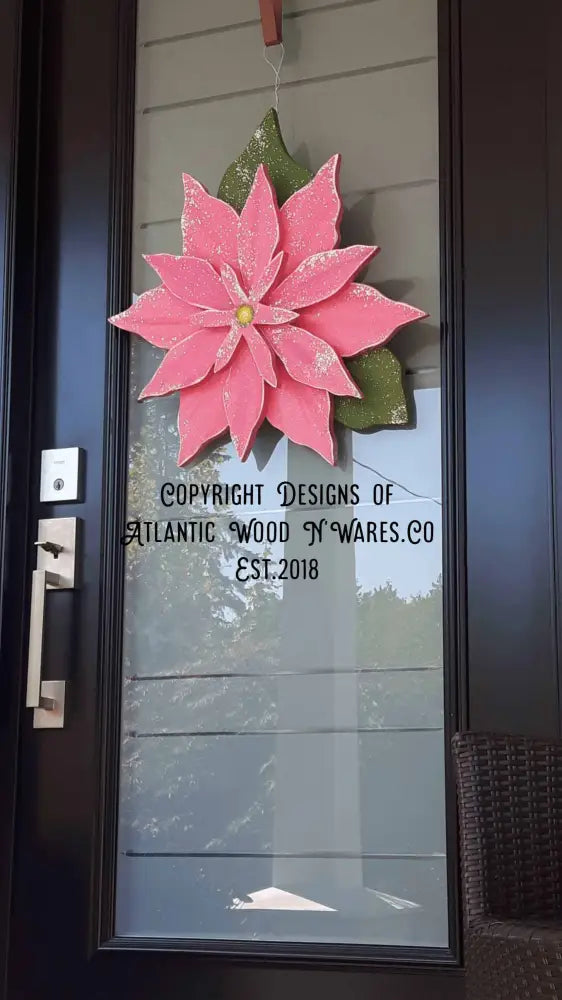 Wooden poinsettia decoration hanging on a glass door.