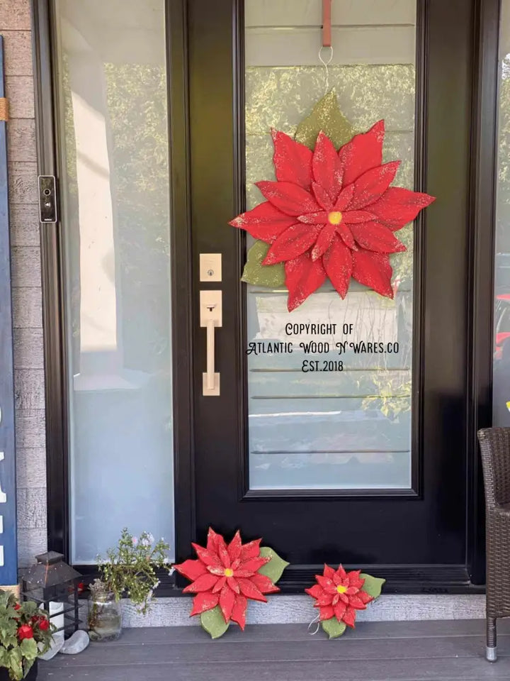 Wooden poinsettia flower decoration on door, symbolizing holiday season with red petals.