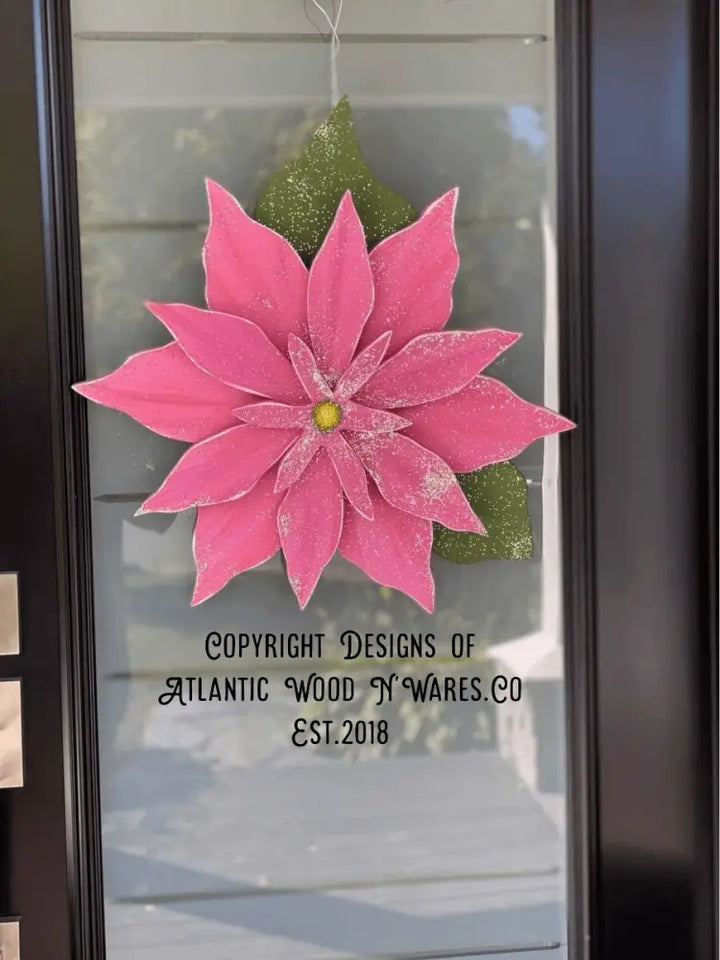 Wooden poinsettia flower decoration for holiday season hanging on door.