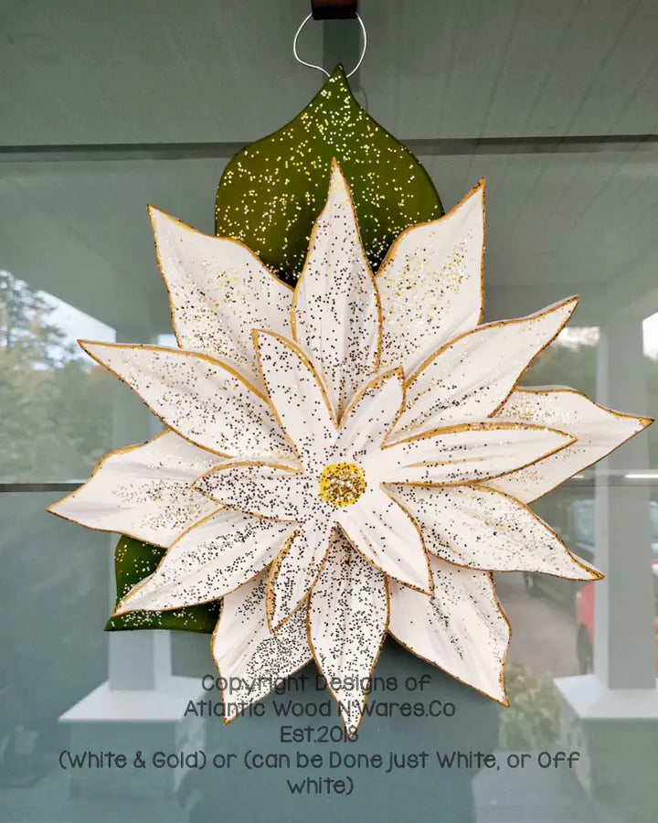 Wooden poinsettia flower in white and gold, designed for holiday decoration, displayed on a door.