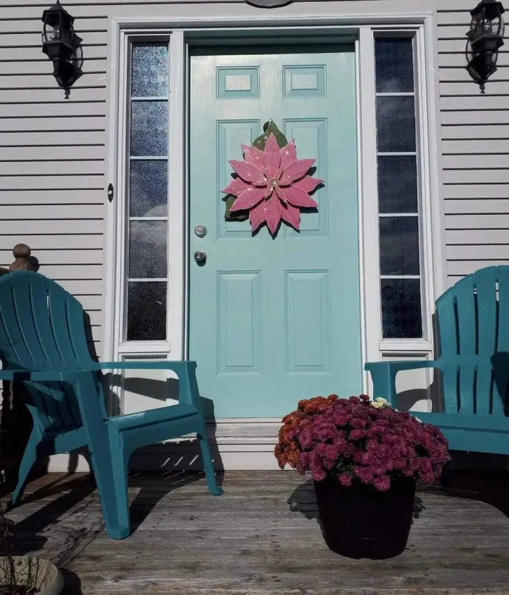 Wooden Poinsettia flower decoration on teal front door, holiday season decor.