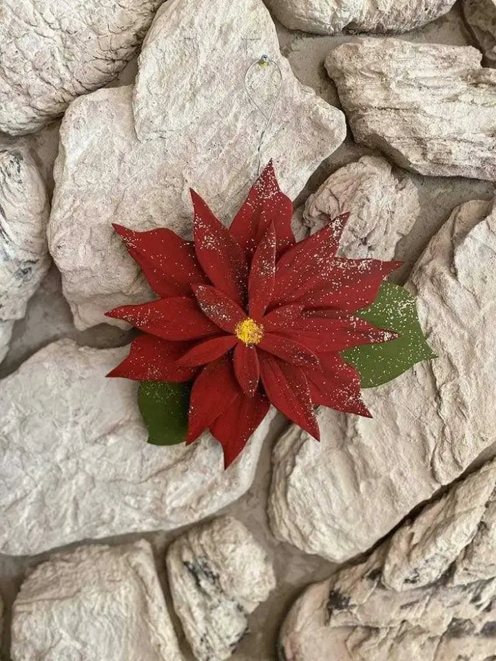 Wooden Poinsettia flower decoration on a textured stone background, symbolizing holiday blessings and everlasting life.