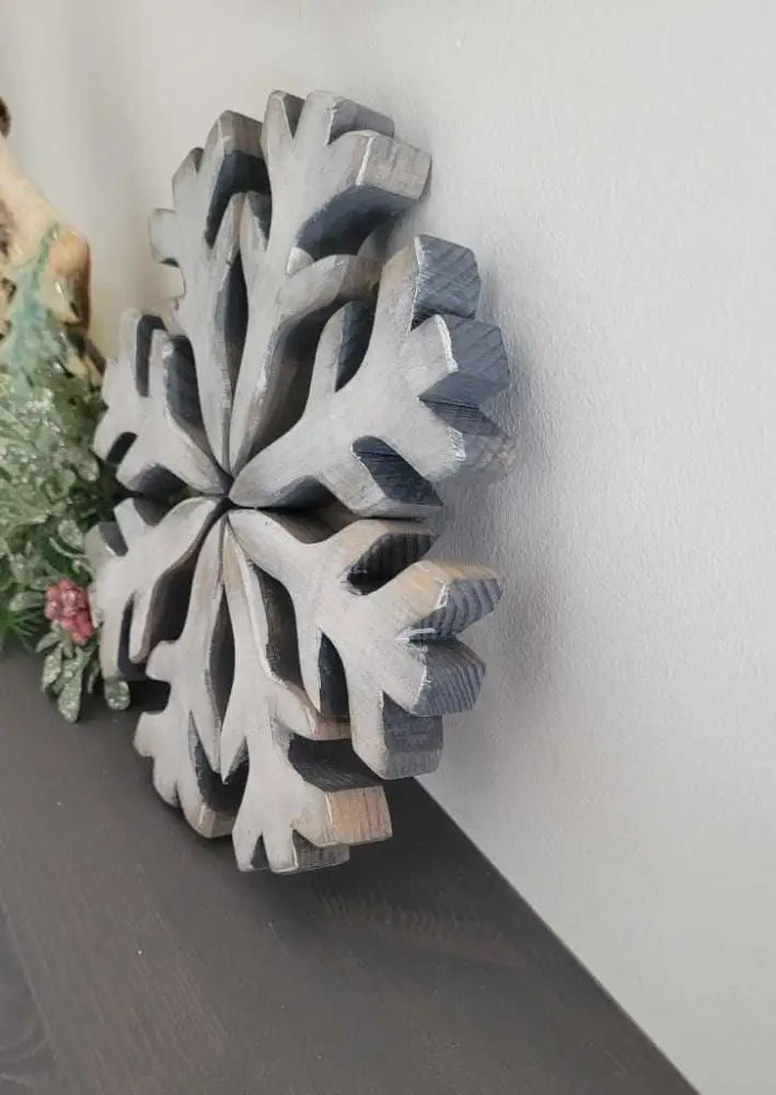 Handmade wooden snowflake decoration with rustic appeal and galvanized wire hanger.