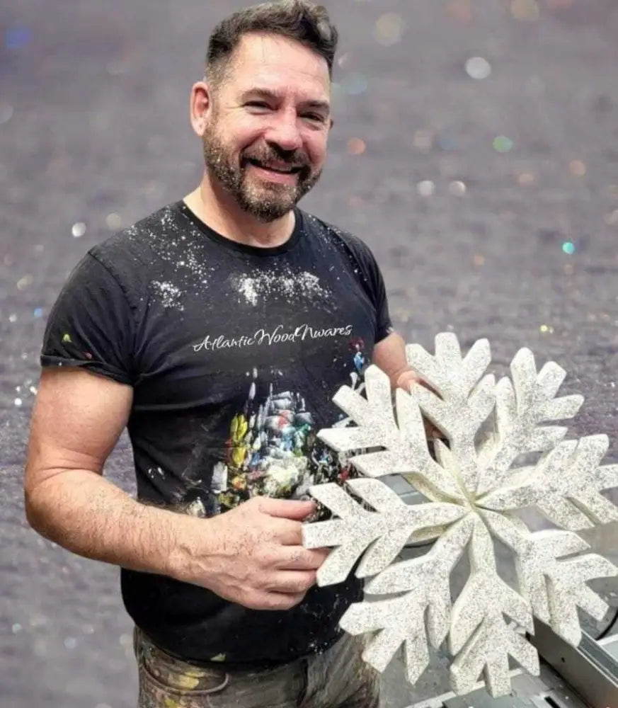 Handmade snowflake decoration held by artisan, featuring glittery design and rustic charm.