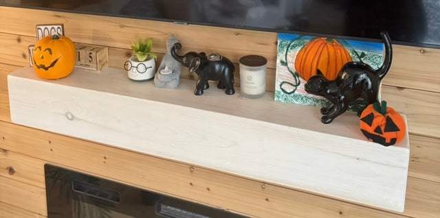 Handcrafted rustic wood fireplace mantel with decorative items, featuring a white wash finish.