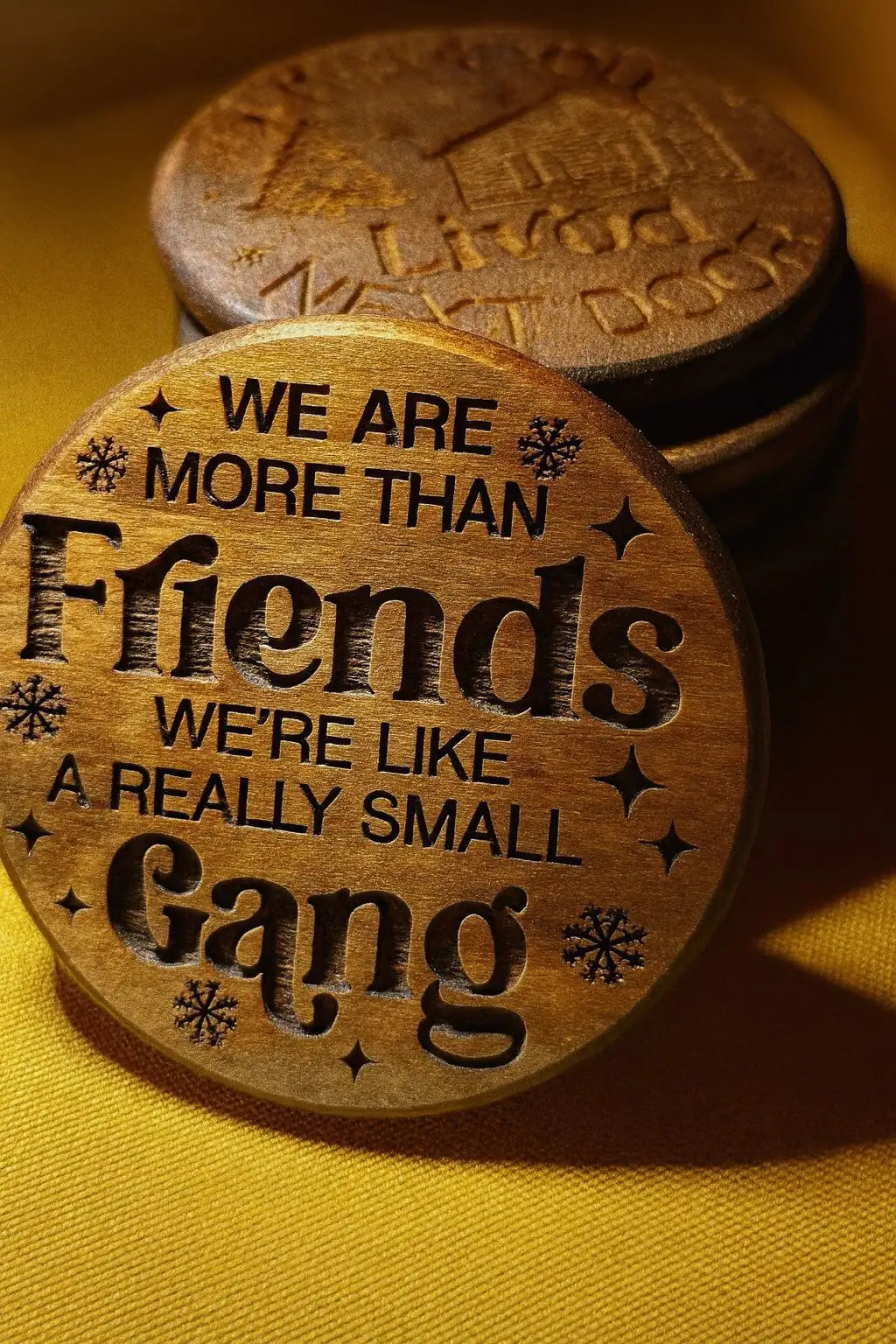 Wooden coaster set with snowflake design and text ’we are more than friends, we’re like a really small gang’ in black lettering.