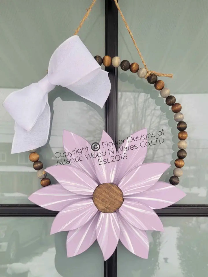 Boho style wooden bead wreath with a painted wood flower and white bow, featuring hand-stained beads.