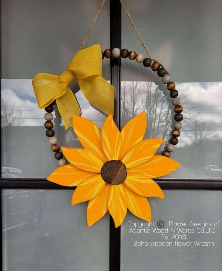 Boho style wooden bead wreath with painted wood flower and yellow bow.