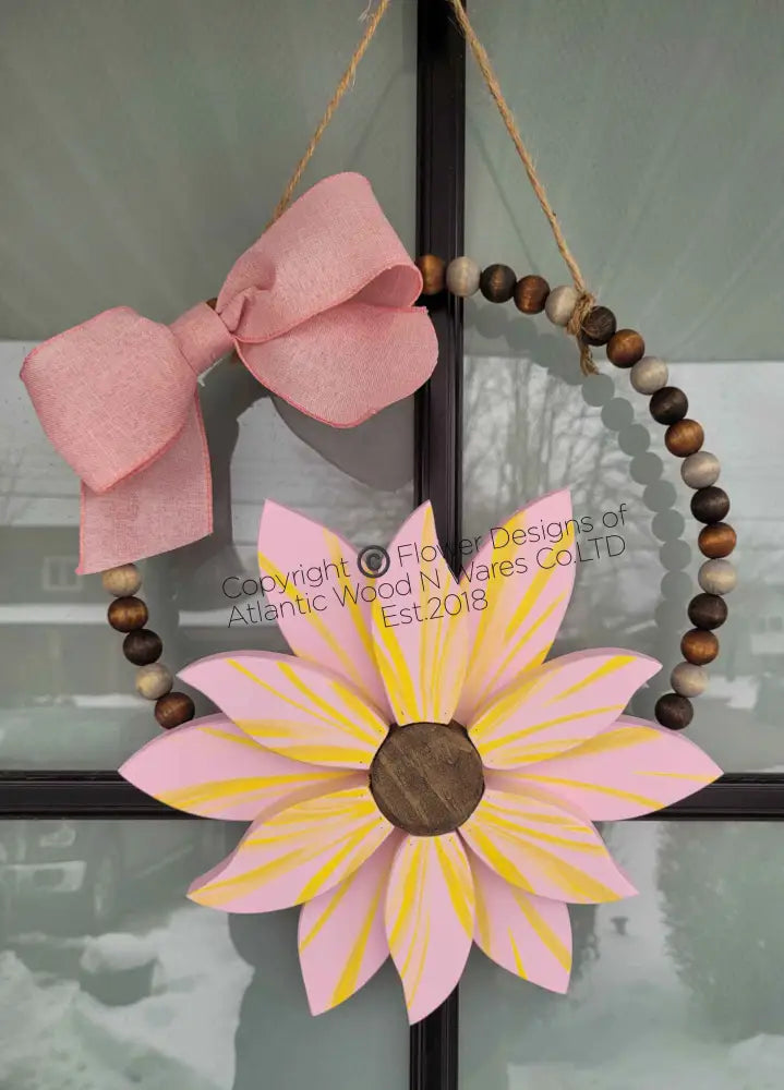 Boho style wooden bead wreath with a painted wood flower and pink bow, featuring hand-stained beads.