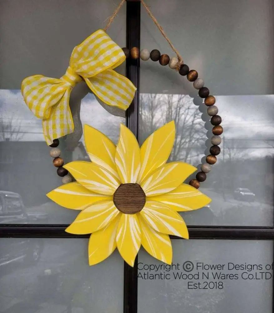 Boho style wooden bead wreath with yellow painted wood flower and gingham bow.