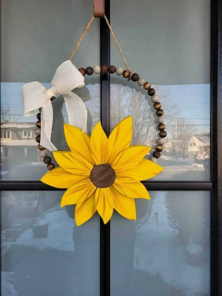Boho style wooden bead wreath with painted wood flower and hand-stained beads hanging on a door.